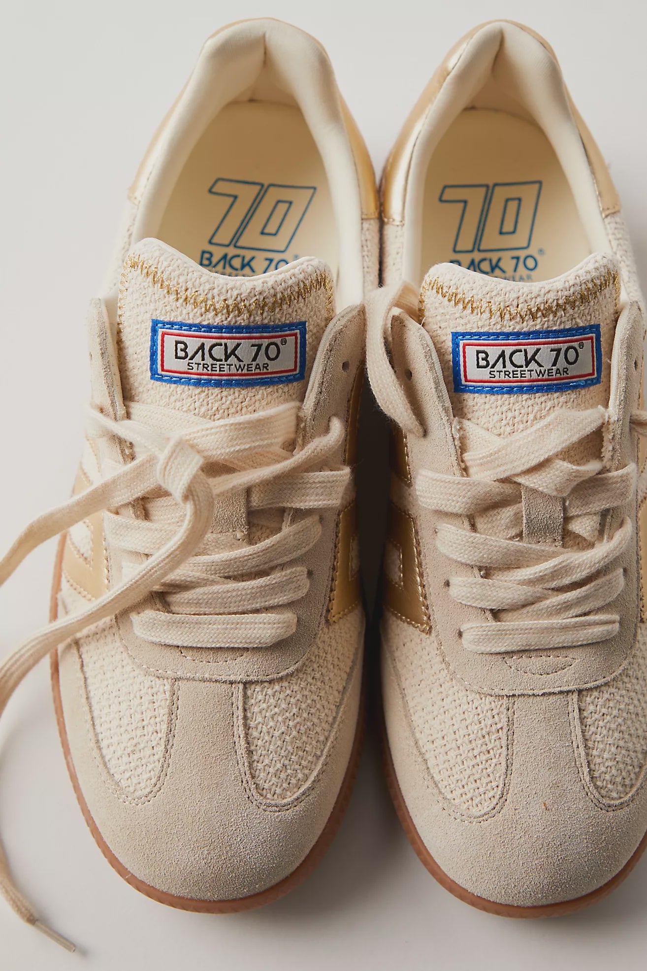 Pair of beige sneakers with 'Back to 70' label on a light background