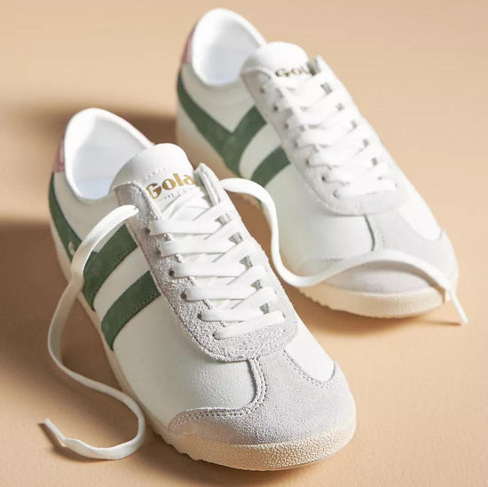 Pair of Gola Pure Sneaker Evergreen in white leather with green suede side stripes, featuring a retro-inspired design and lace-up closure on a beige background