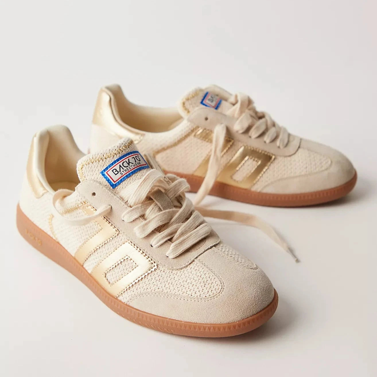 Pair of beige sneakers with brown soles on a light gray background