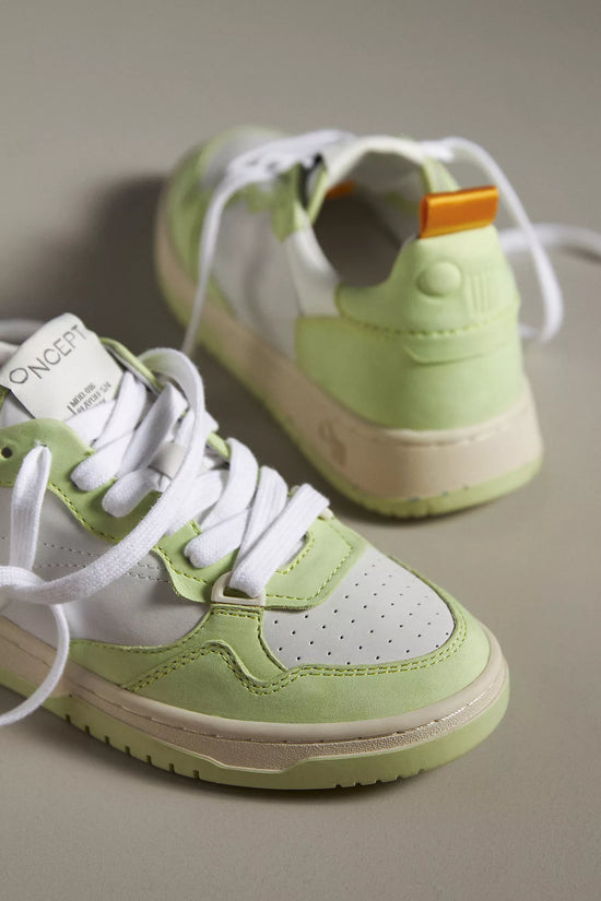 A close-up view of the Oncept Sneakers Phoenix NYC in Green Matcha colorway, focusing on the details of the white and light green leather panels, white laces, and the branding on the tongue. The sneakers have a clean and modern look with an orange pull tab at the back