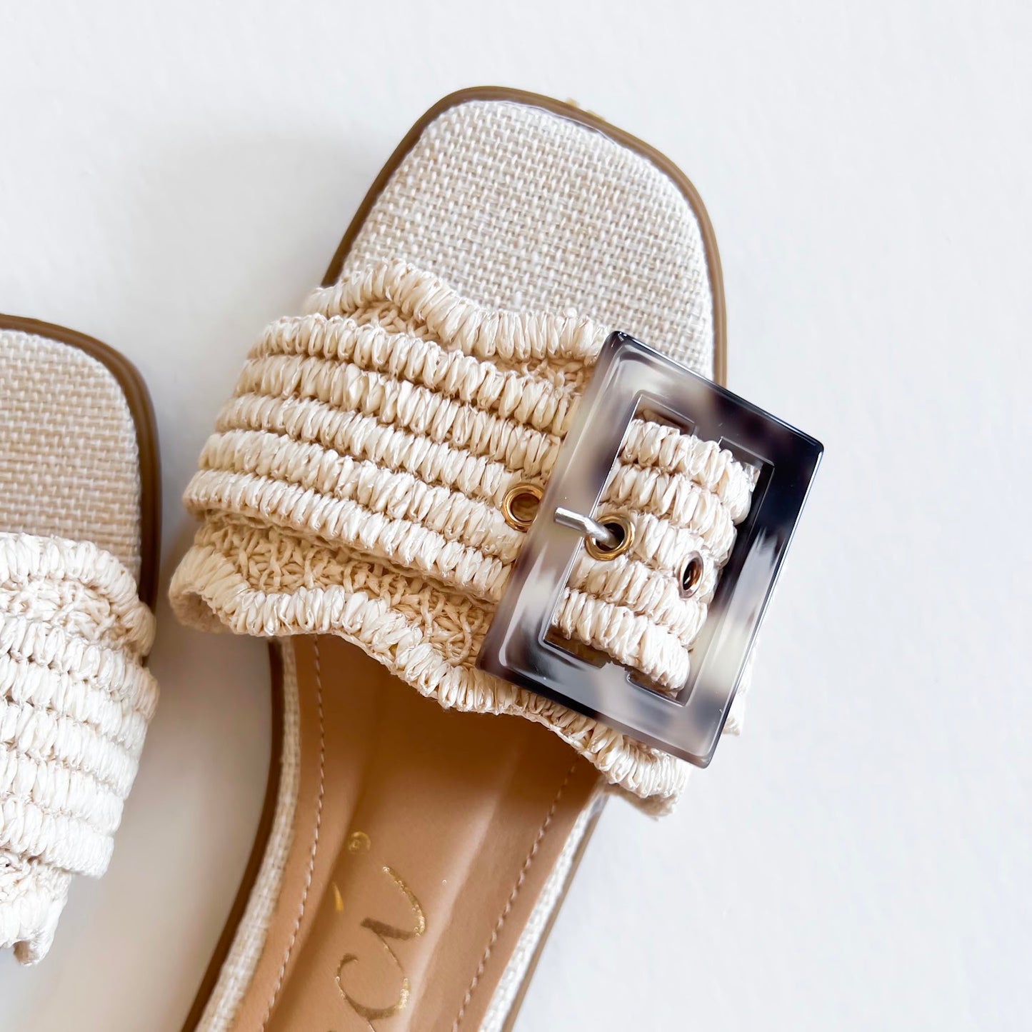 Stylish beige sandals with a textured strap and oversized buckle, perfect for summer fashion