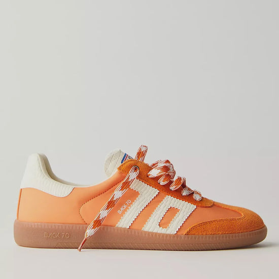 Bright orange retro-style sneakers with white stripes, suede detailing, gum soles, and patterned orange-and-white laces