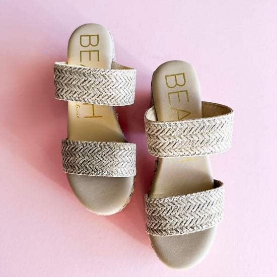 A pair of Beach by Matisse Ocean Ave Platform Sandals with a woven raffia-textured design, featuring double straps and a chunky heel, displayed on a pastel pink background. Stylish and comfortable summer footwear perfect for casual outings and vacations