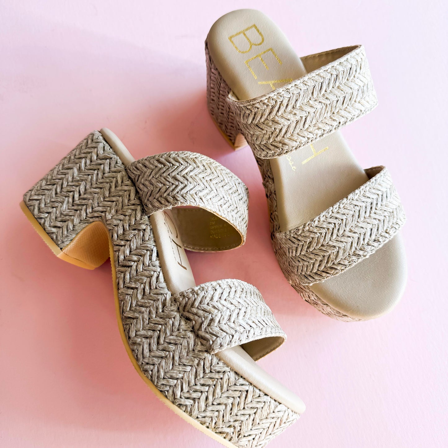 A pair of Beach by Matisse Ocean Ave Platform Sandals with a woven raffia-textured design, featuring double straps and a chunky heel, displayed on a pastel pink background. Stylish and comfortable summer footwear perfect for casual outings and vacations