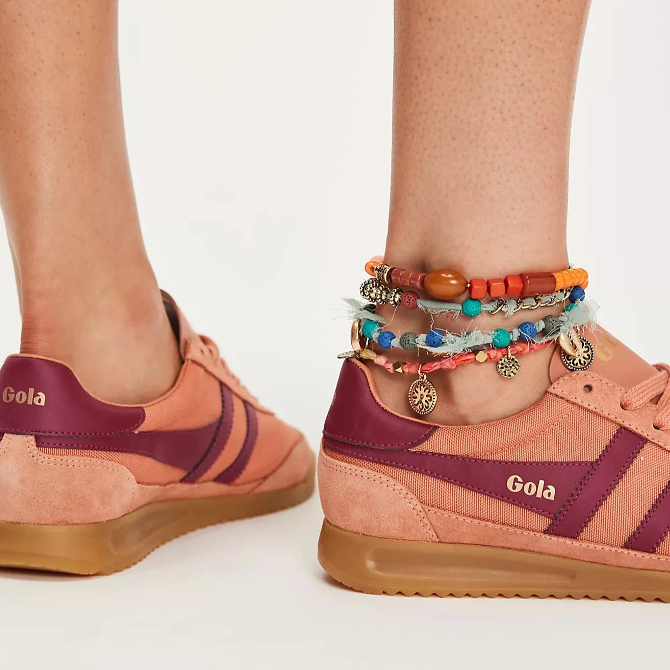 Side view of a Gola Tornado sneaker featuring a terracotta canvas and suede upper, burgundy leather stripes, gold Gola branding, and a gum rubber sole.