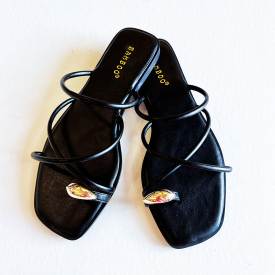 Pair of black strappy toe ring sandals for women, featuring sleek straps and a stylish toe ring.