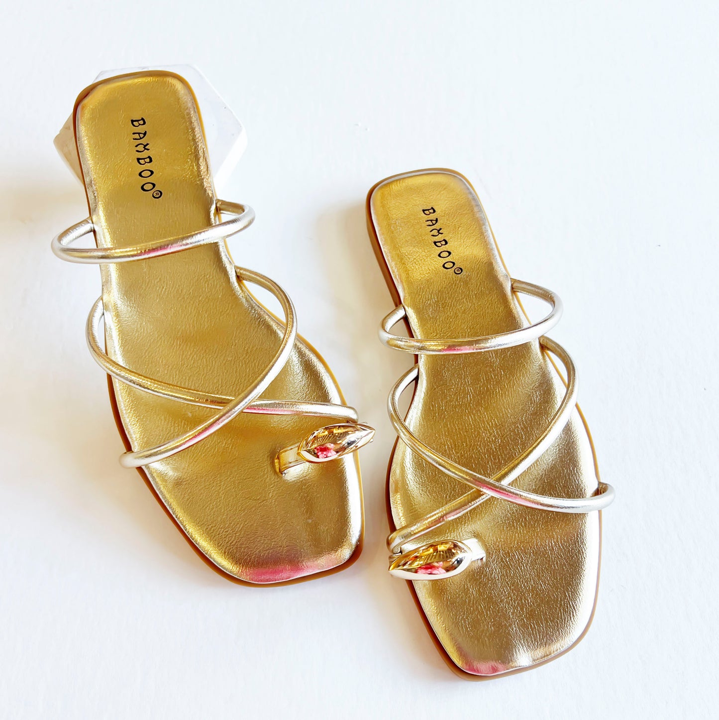 Pair of gold strappy toe ring sandals for women, showcasing metallic straps and a chic toe ring.