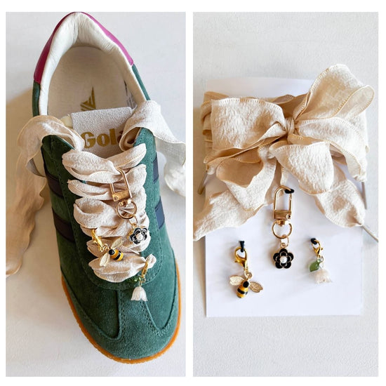 Green sneaker with decorative lace featuring bee and flower charms, cream-colored fabric laces, and a gold keychain attachment